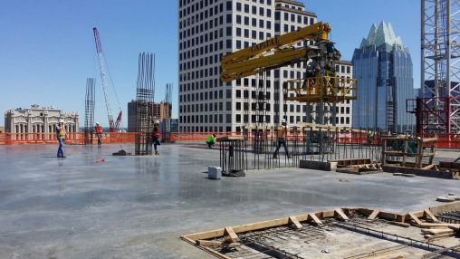 Freshly poured and finished concrete deck of the 14th floor – first pour (eastern third).  The concrete is pumped by a pumper truck from a continuous stream of trucks on 7th Street down to the Basement and up through the yellow pumper rig on the right.