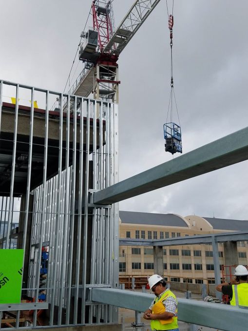 A manlift is being hoisted to the roof by the tower crane for work on the mechanical penthouse.  The mechanical penthouse is on the left side of the photo.
