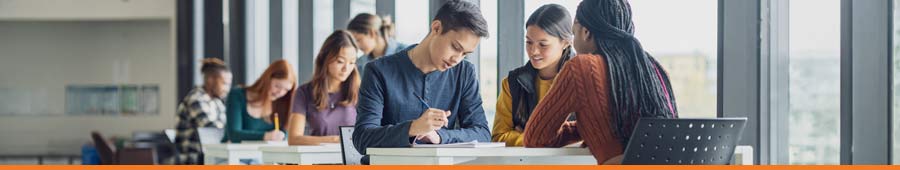 Students studying at tables looking at laptops