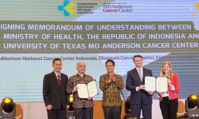 Leaders from Indonesia and MD Anderson, dr. Soeko Nindito, dr. Sunarto, Budi Sadikin, Chris McKee and Dr. Kathleen Schmeler, standing before a crowd holding up a signed documents for the official collaboration efforts