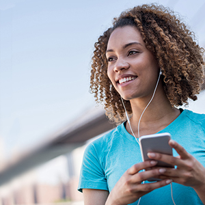 African American woman in t-shirt wearing earphones and holding phone