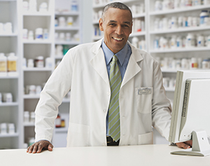 A pharmacists at a counter smiling