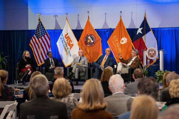 Panel talking in front a collection of flags