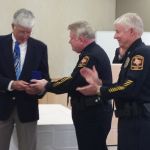 Director Heidingsfield and Senior Police Inspector Bobby Harper present UT System pilot Rick Khalar with a UT System Police badge as "CHIEF PILOT" in appreciation for his service to the UTSP upon his retirement from the UT System