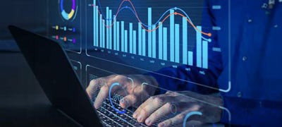 Pair of hands typing with data graphs on screens