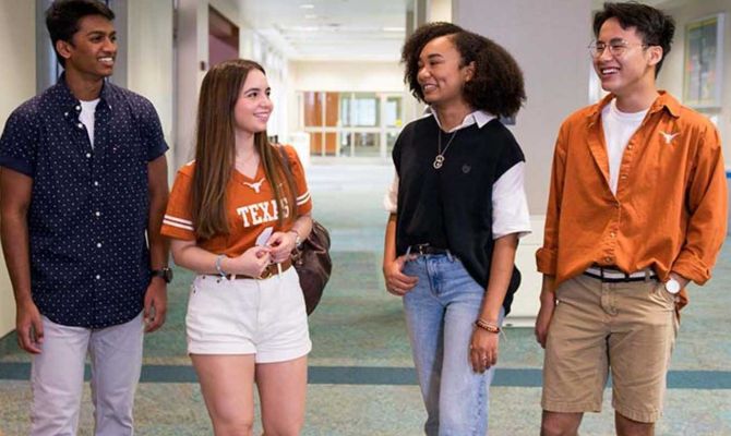 Diverse group of college students from UT Austin, talking in a hallway