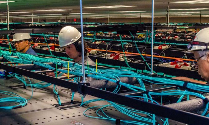 TACC employees work on the network cabling above the racks of Frontera.