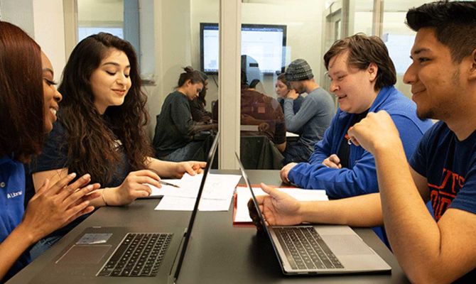 Students at a table working on their laptops