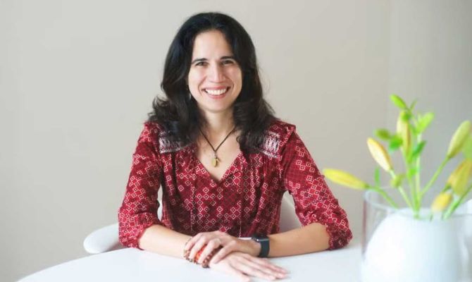 Lorena Moscardelli profile photo sitting at a table looking at the camera