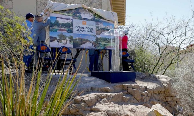 University staff unveil an outdoor sign detailing improvements to Arroyo park
