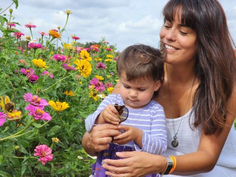 Crystal Clabes, Senior Facility Manager, holding her small child in a field of flowers